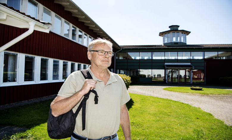 Mikael Jönsson, sjuksköterska, står utanför en byggnad och blickar bortom kameran.