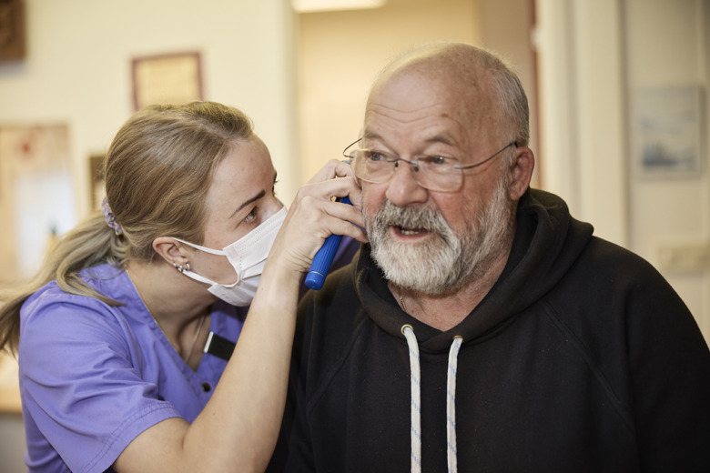Sjuksköterskan Evelina Markström tittar in i örat på patienten Reino Niemi i sin undersökning av hans nedsatta hörsel.