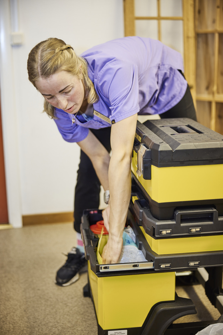 Sjuksköterskan Evelina Markström står böjd över en stor vårdväska på hjul som är inspirerad av en stor verktygslåda som hennes sambo hade hemma.