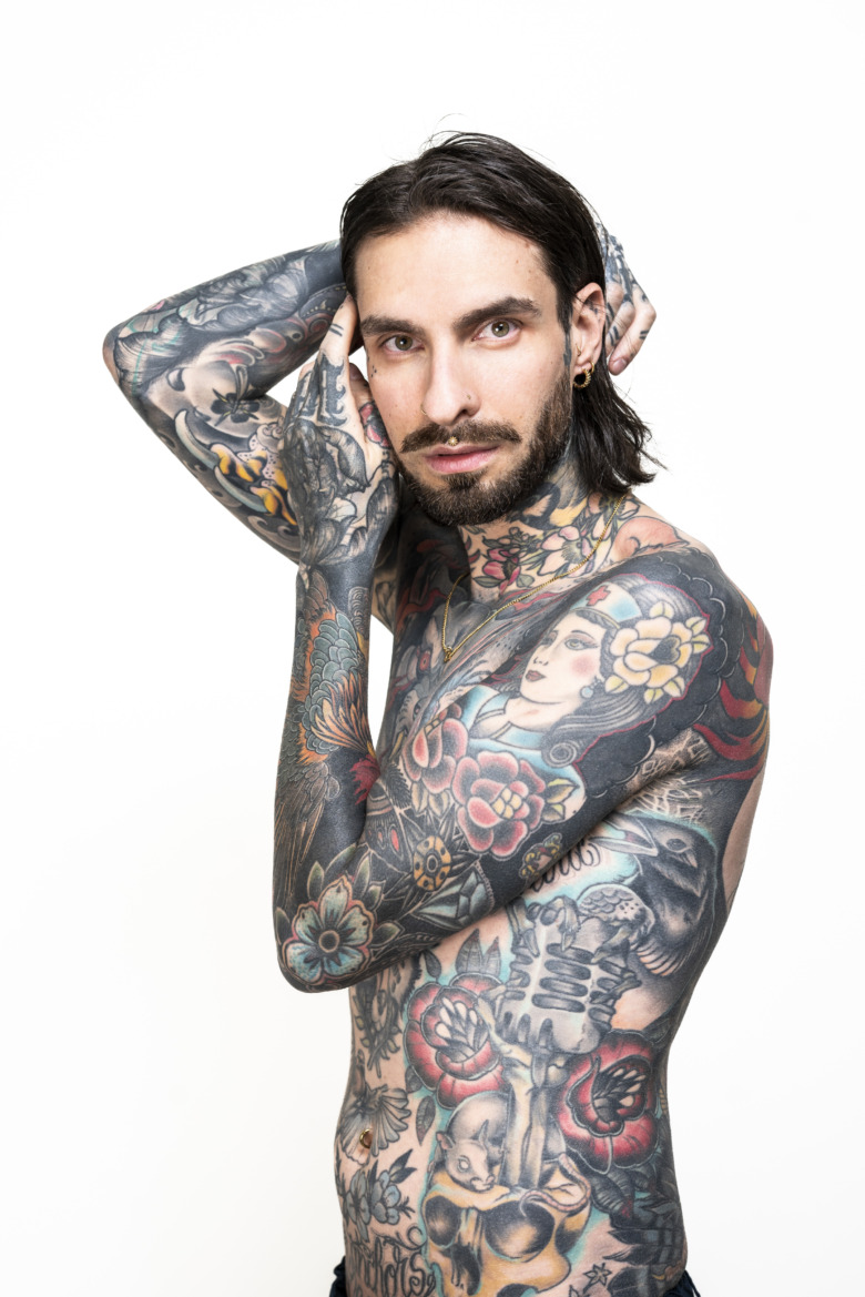 En halvkroppsbild på Daniel Mårs som utan tröja visar upp sin heltatuerade överkropp. Huden från midja och ända ut till fingerspetsarna är fulla av tatueringar.