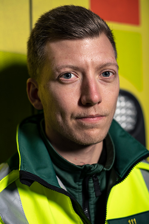 En nära porträttbild på Elias Hedlund som lutar sig med ryggen mot en ambulans