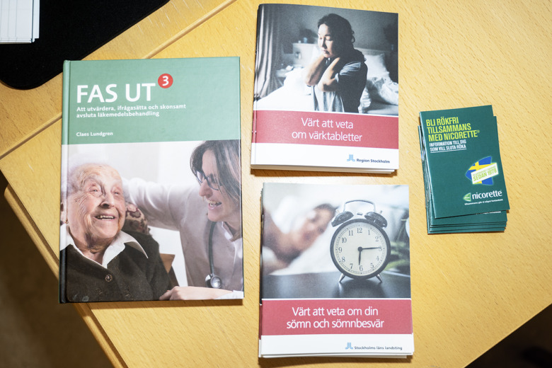 Boken "FAS UT 3" av Claes Lundgren, Region Stockholms broschyrer "Värt att veta om värktabletter" och "Värt att veta om din sömn" och sömnbesvär, samt Nicorettes "Bli rökfri tillsammans med Nicorette" ligger samlade på ett skrivbord.