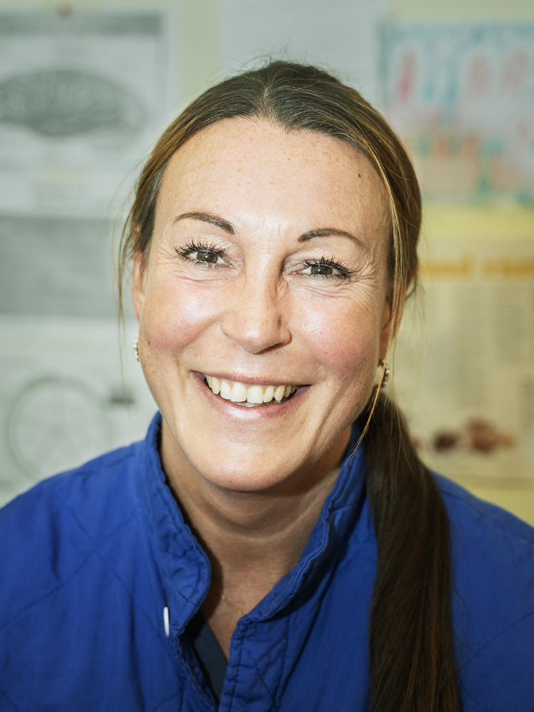 Porträtt på distriktssjuksköterskan Carina Holmberg på Hässelby vårdcentral. Hon ler, har bruna ögon, långt brunt hår i en hästsvans, och bär en blå väst. Hon jobbar för att minska läkemedelsberoende bland sina patienter.