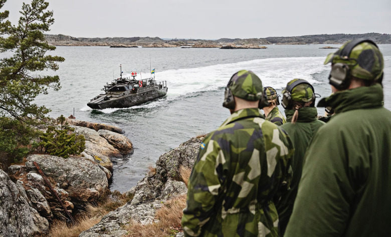 En sjukvårdsbåt av modell stridsbåt 90 kör mellan öarna i Göteborgs skärgård. Deltagare i 48H ser på från land. 48H är Försvarsmaktens prova-påkurs för vårdpersonal, en helg av föreläsningar som varvas med praktiska övningar i militärsjukvård och soldatliv.