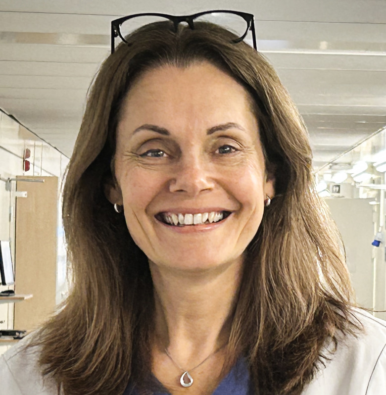 Sjuksköterskan Veronica Dalevi, iförd arbetskläder, står i en sjukhuskorridor.