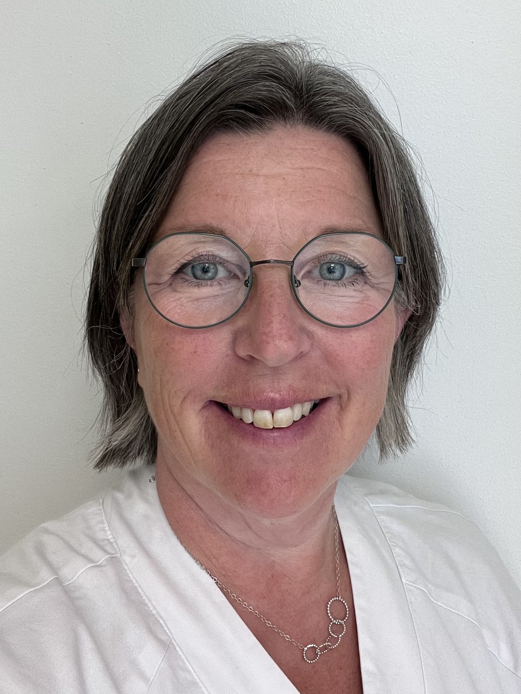 Porträtt på Anna-Lena Hansson, som ler in i kameran med vita arbetskläder.