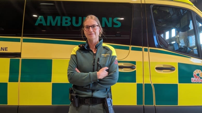 Ambulanssjuksköterskan Johanna Uppenberg i uniform står framför en ambulans.