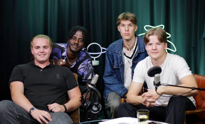 Love Runesson och tre andra killar sitter vid ett bord i en inspelningsstudio som har tyg draperat över väggen och gröna växter i bakgrunden. De har mikrofoner framför sig. De tittar in i kameran.