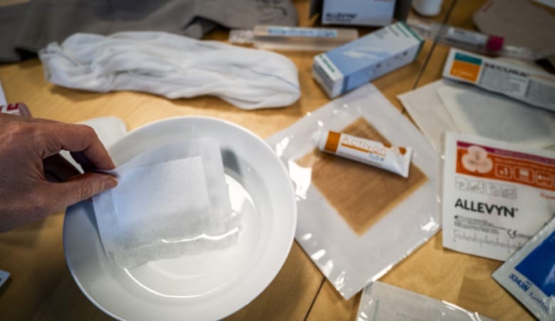 Ett superabsorberande förband doppas i vatten. Bredvid ligger andra förband och artiklar som används i kommunernas sårbehandling.