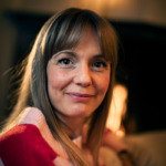 Portätt av Emma Fagerberg. Hon har långt cendréfärgat hår, lugg och bär en rosa och röd tröja.