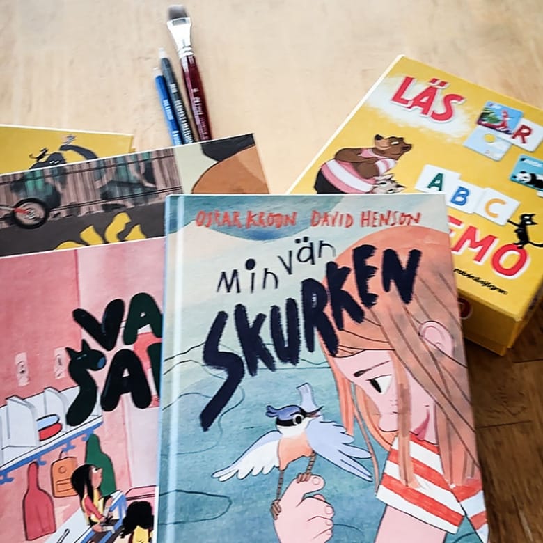 Flera barnböcker staplade på varandra, penslar samt ett memoryspel.