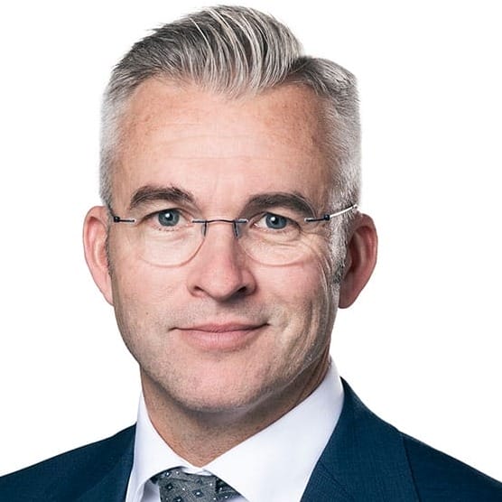 Porträtt av Stellan Ahlström, sjukhuschef Skaraborgs sjukhus. Han har ljust bakåtkammat hår, bär glasögon, vit skjorta, mörkblå kavaj och slips.