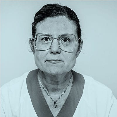 Porträtt av Ulla Olsson Strömberg. Hon bär glasögon, halsband, bussarong med mörkare kant runt halslinningen och glasögon. Hon tittar in i kameran.