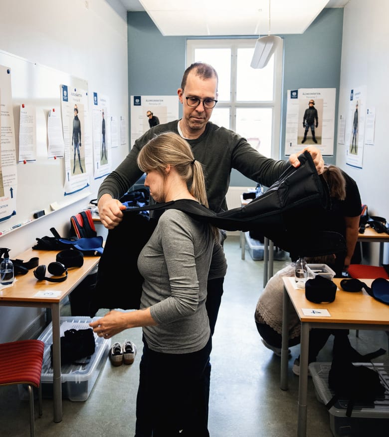 En man hjälper en kvinna att klä på sig en tyngdväst.